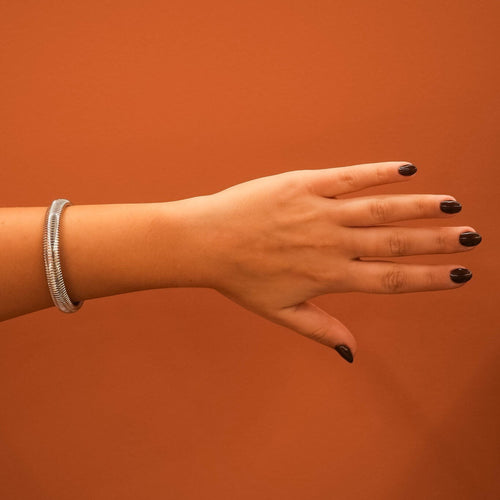 Pulseira Lifeaskika Classic Chain em aço inoxidável prateado no pulso de uma mulher com fundo laranja